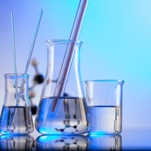 Imagem com 3 potes de vidros utilizados em química meio cheios com líquidos transparentes. Um jogo de cores na paleta azul.